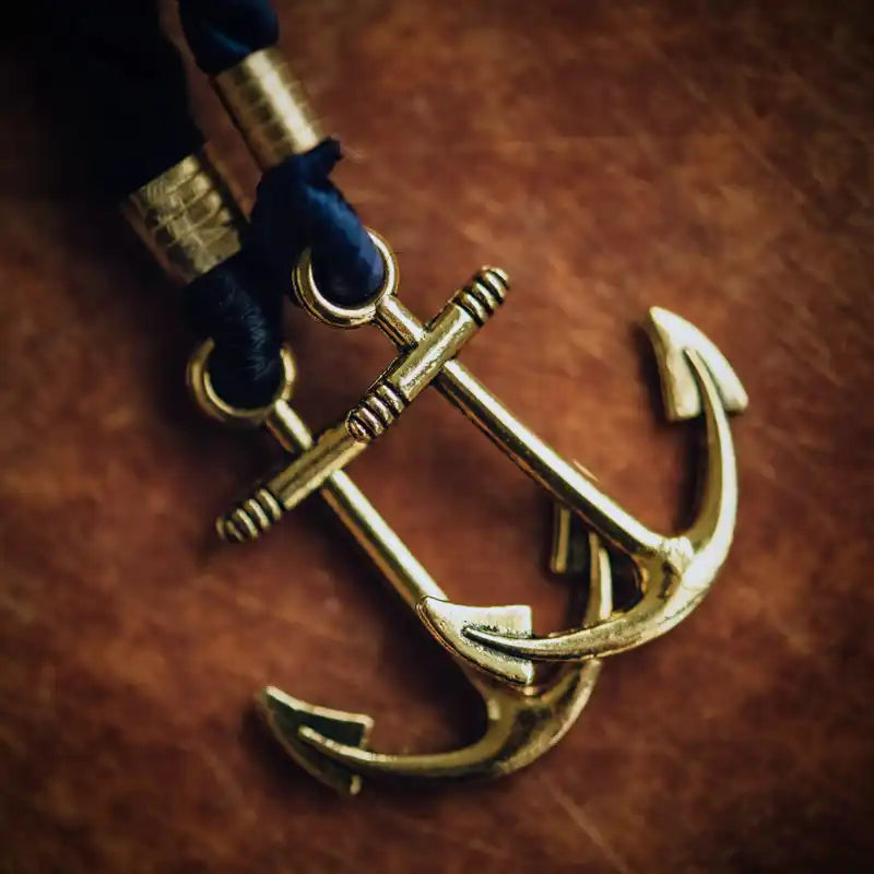 Deux pendentifs d'ancre de couleur or avec un cordon bleu.